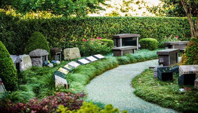 Pathway through a cremation garden in a cemetery with niches, boulders and benches. 